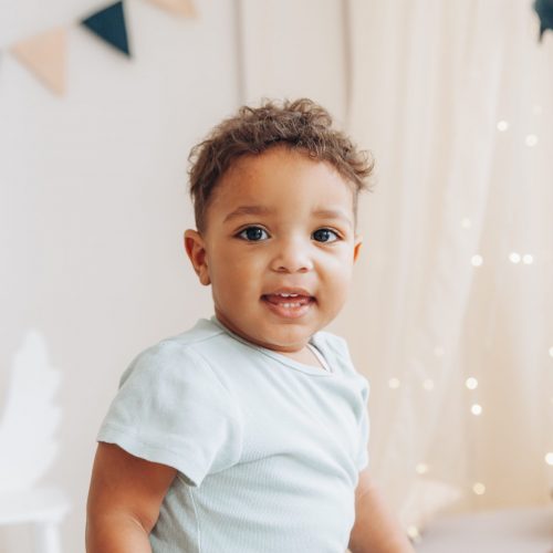 A cute little african american boy sits on a highchair in the shape of an elephant.children's room design.